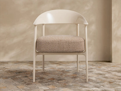 Nia Outdoor Dining Chair, light beige molded frame and speckled brown cushion, angled right on a stone tiled floor.