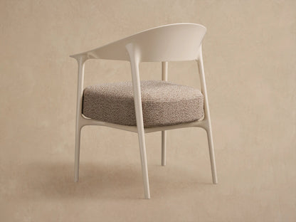 Close-up of Nia Outdoor Dining Chair: light beige frame with curved back/armrests, textured beige seat cushion, angled view.