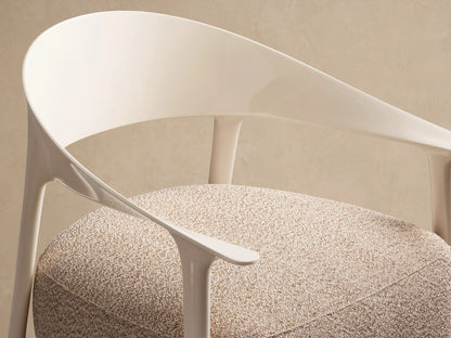 Nia Outdoor Lounge Chair: off-white frame with curved back, textured light brown cushion, on a tiled floor.