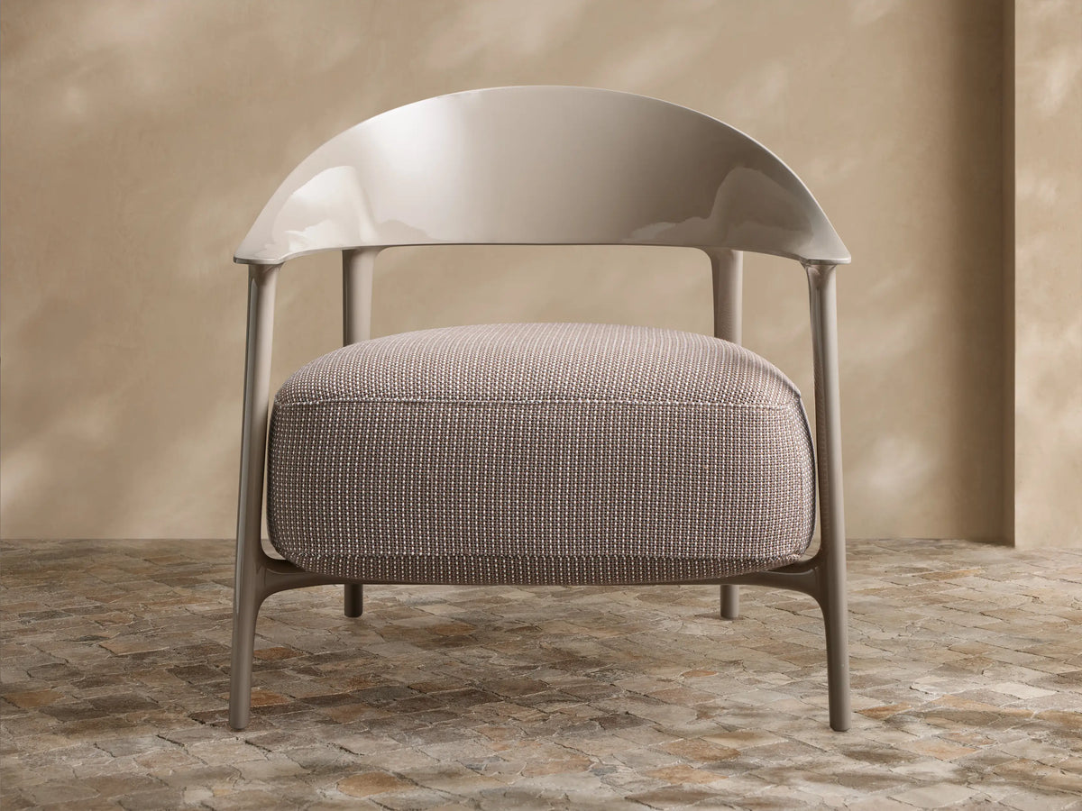 Nia Outdoor Lounge Chair with a light gray polypropylene frame, curved back, integrated arms, and a textured beige patterned cushion.