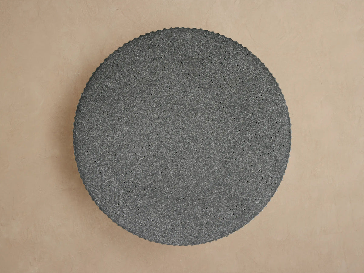 Close-up of the dark gray Ojai Outdoor End Table, featuring a round, smooth top and textured vertical fluted sides.