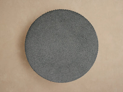 Close-up of the dark gray Ojai Outdoor End Table, featuring a round, smooth top and textured vertical fluted sides.