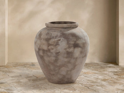 Large Olivio Outdoor Planter with weathered antico terracotta finish, rounded ceramic on light stone pavers against a beige wall.