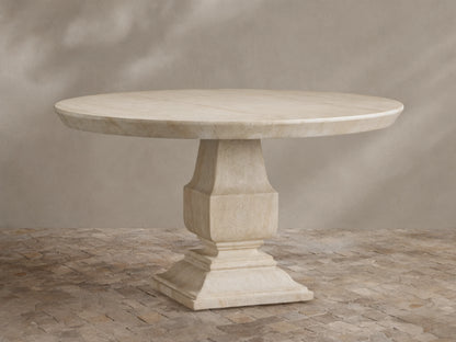 Primrose Outdoor Round Dining Table in light beige GFRC, round top with subtle grey veining, on a sculpted pedestal base, on tiles.