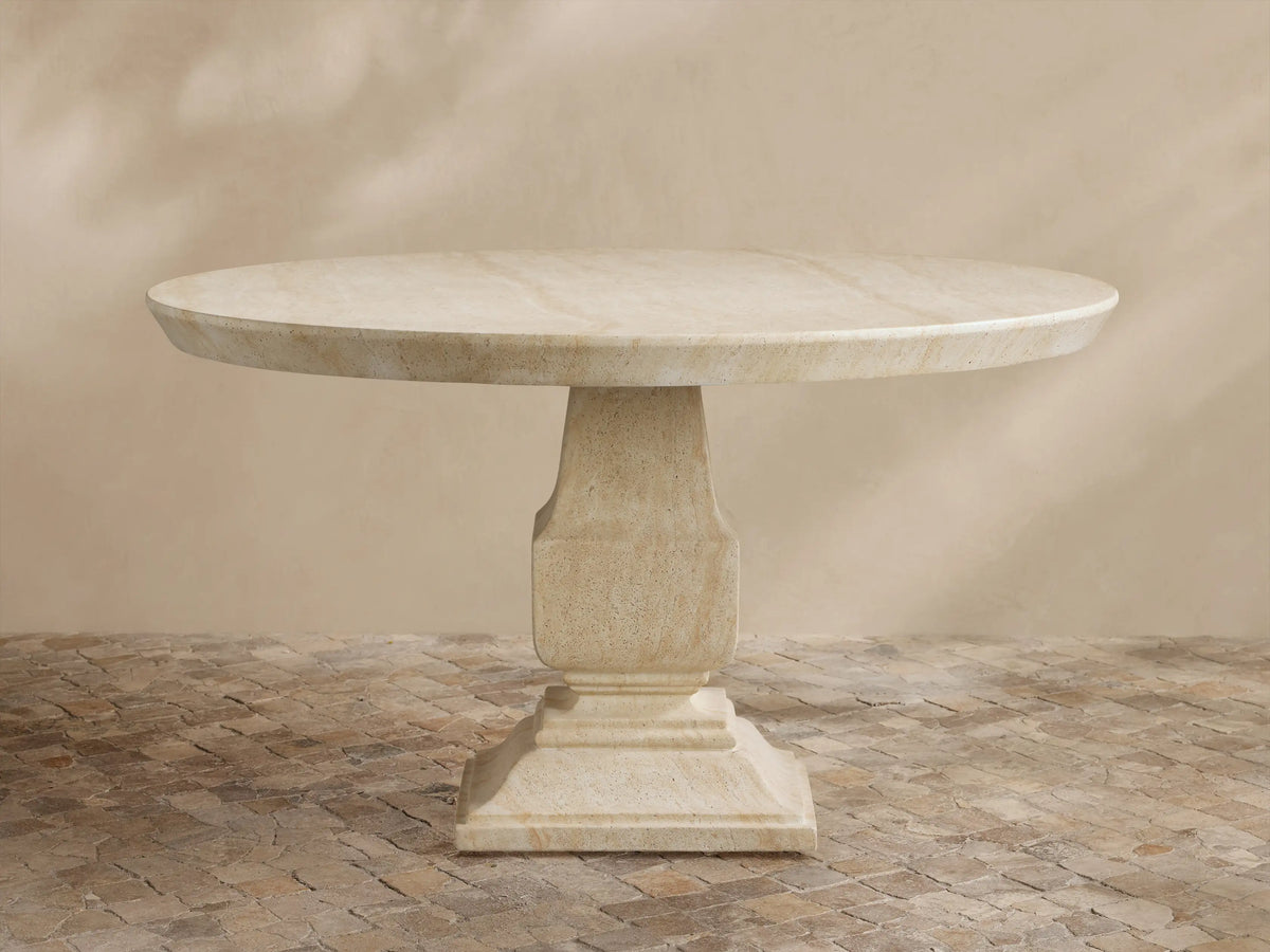 Primrose Outdoor Round Dining Table in light beige GFRC, round top with subtle grey veining, on a sculpted pedestal base, on tiles.