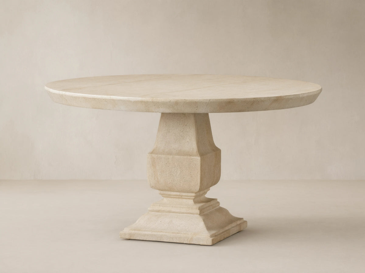 Primrose Outdoor Round Dining Table in light beige GFRC, round top with subtle grey veining, on a sculpted pedestal base, on tiles.