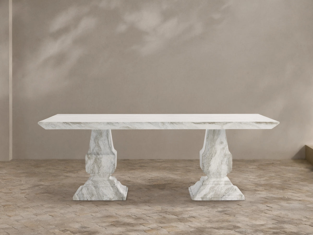 Primrose Outdoor Dining Table with rectangular white-grey marbled top and two sculpted pedestal bases on a tiled patio.