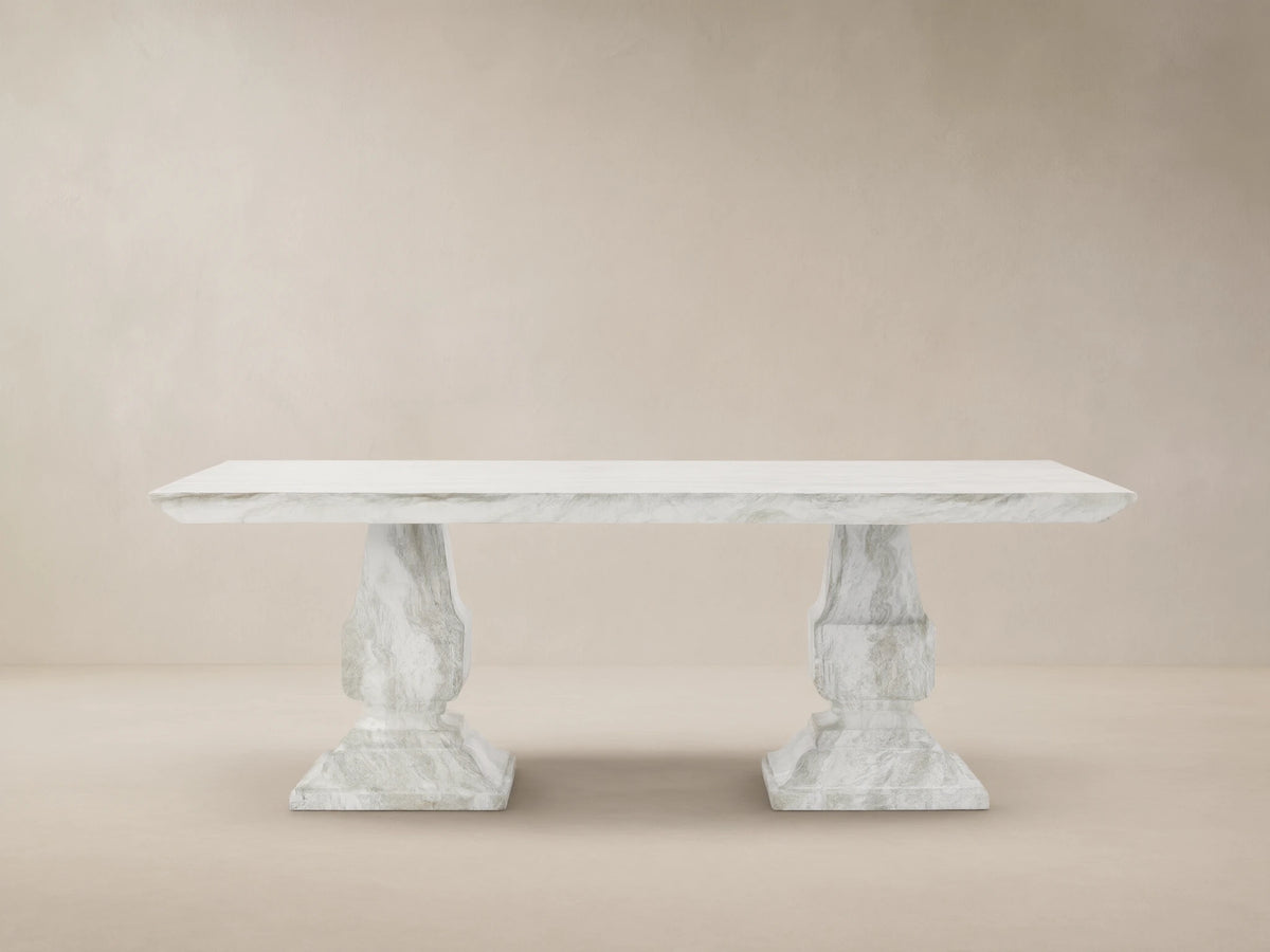 Primrose Outdoor Dining Table with rectangular white-grey marbled top and two sculpted pedestal bases on a tiled patio.