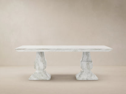 Primrose Outdoor Dining Table with rectangular white-grey marbled top and two sculpted pedestal bases on a tiled patio.