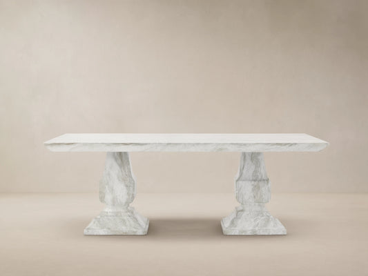 Primrose Outdoor Dining Table with rectangular white-grey marbled top and two sculpted pedestal bases on a tiled patio.