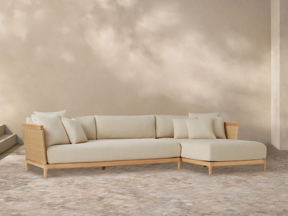 Puglia Outdoor Teak Two-Piece Sectional with right-hand chaise, light cream cushions, natural teak frame, and woven accents.