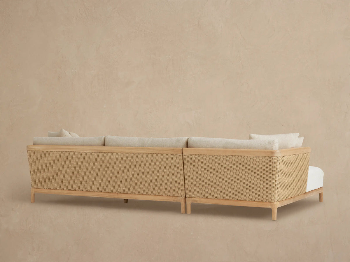 Close-up of Puglia Outdoor Teak Sectional with light beige textured cushions, natural teak armrest, and woven wicker panel.