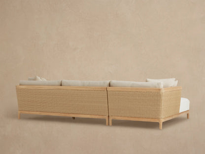 Close-up of Puglia Outdoor Teak Sectional with light beige textured cushions, natural teak armrest, and woven wicker panel.