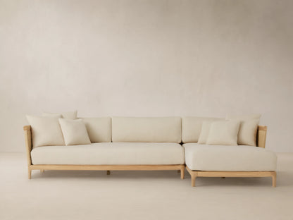 Puglia Outdoor Teak Two-Piece Sectional with Chaise, light teak L-shaped frame, cream cushions & toss pillows, woven accents.
