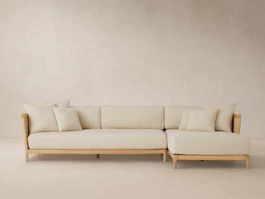 Puglia Outdoor Teak Two-Piece Sectional with Chaise, light teak L-shaped frame, cream cushions & toss pillows, woven accents.