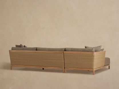 Puglia Outdoor Teak Sectional close-up: natural teak arm, woven light brown resin wicker side, and textured taupe cushions.