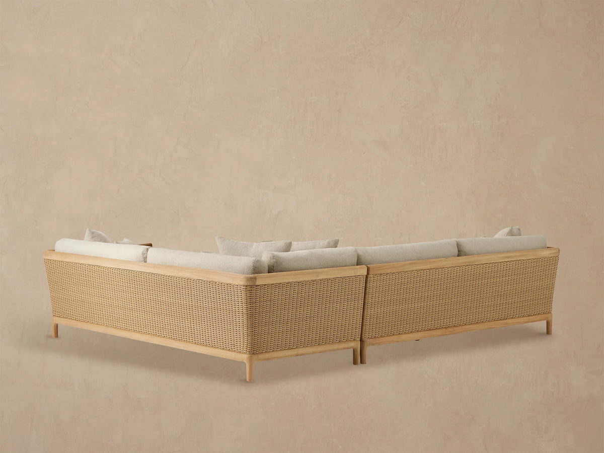 Puglia Outdoor Teak Sectional armrest in natural teak and woven wicker, with light beige textured cushions.