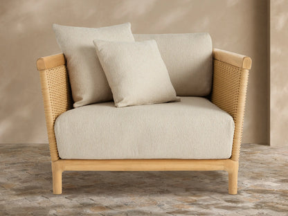 Light grey Puglia Outdoor Collection Cover tailored over a chair. Textured fabric with central seam, on a stone patio against a warm wall.