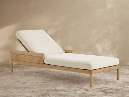 Puglia Outdoor Teak Chaise with reclined backrest, light cream cushions, & woven side panel on patio.