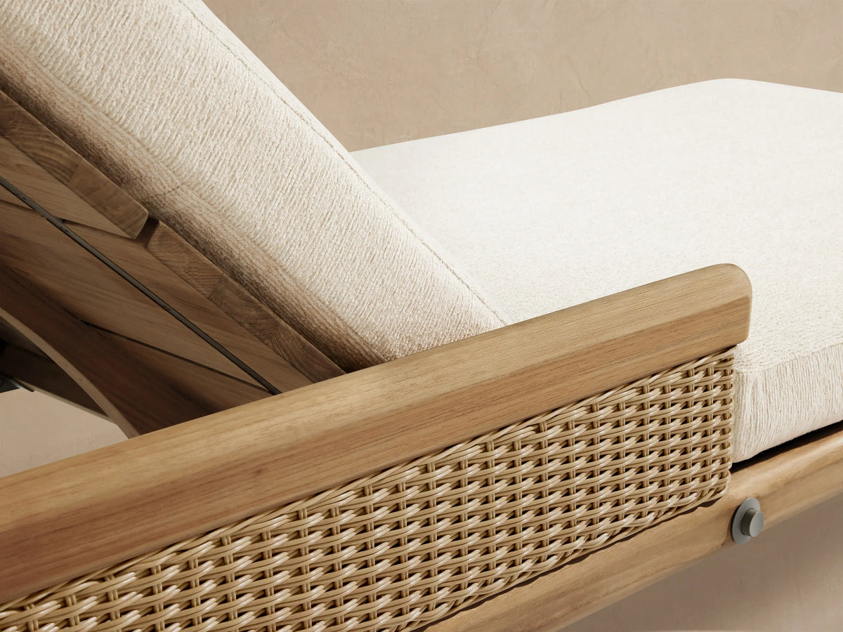 Side view of Puglia Outdoor Teak Chaise with raised headrest, natural teak frame, woven side panel, and light cream cushions.
