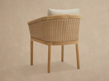 Puglia Outdoor Teak Dining Chair with natural teak frame, light brown woven sides, and cream-colored cushions.