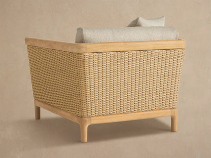 Puglia Outdoor Teak Lounge Chair close-up. Beige cushions, natural teak armrest, woven tan resin wicker side panel.