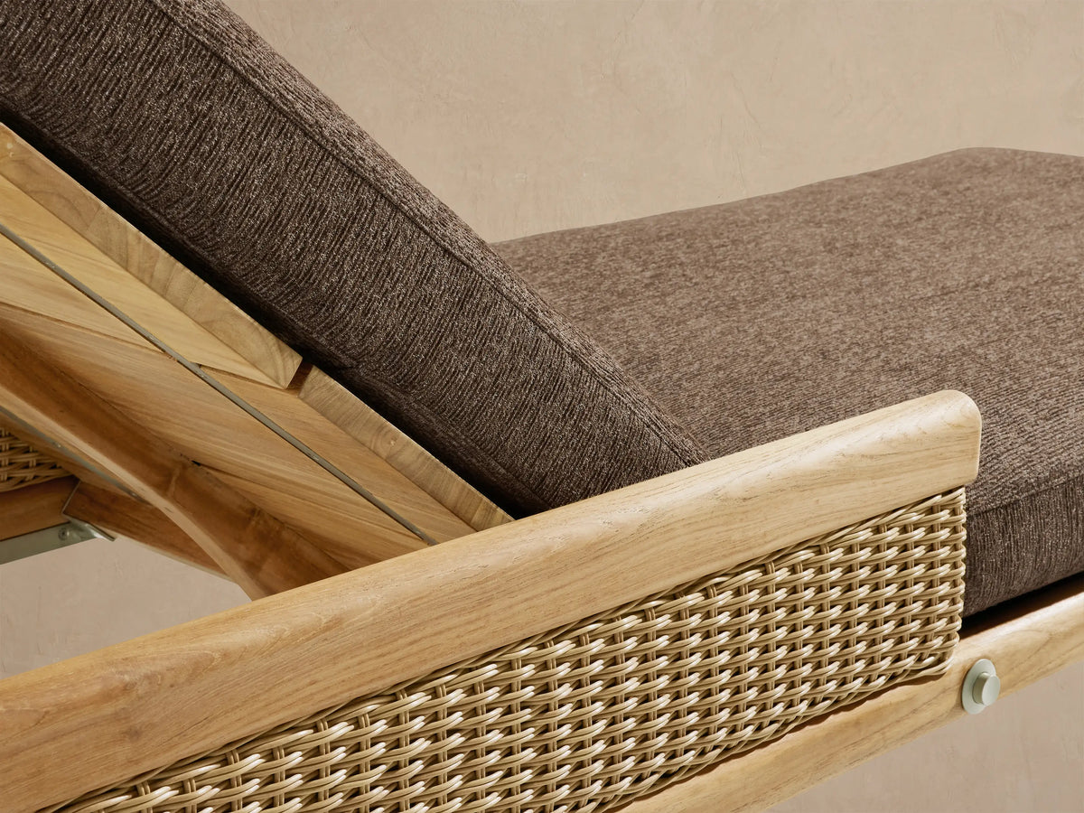 Side view of Puglia Outdoor Teak Chaise with light wood frame, woven side panel, and reclined brown cushion.