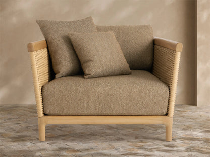 Puglia Outdoor Teak Lounge Chair, light natural teak wood frame, tan woven sides, and plush light brown cushions, on a tiled patio.