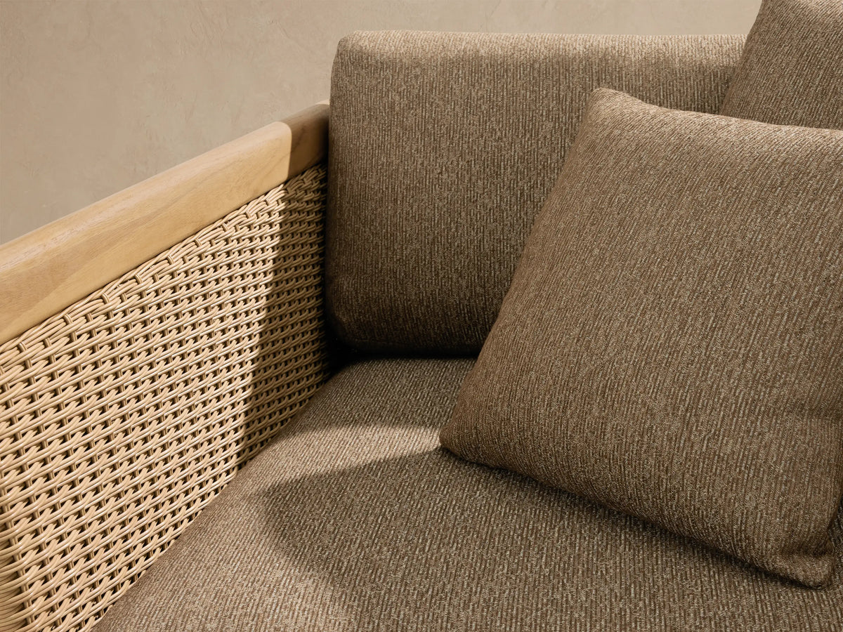Puglia Outdoor Teak Lounge Chair. Natural teak frame, woven light tan resin wicker, and textured medium brown cushions with pillows.