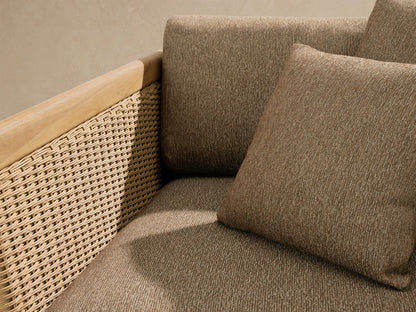 Puglia Outdoor Teak Lounge Chair. Natural teak frame, woven light tan resin wicker, and textured medium brown cushions with pillows.