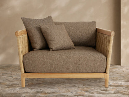 Puglia Outdoor Teak Lounge Chair with natural teak frame, tan woven wicker sides, and deep beige textured cushions with two toss pillows.