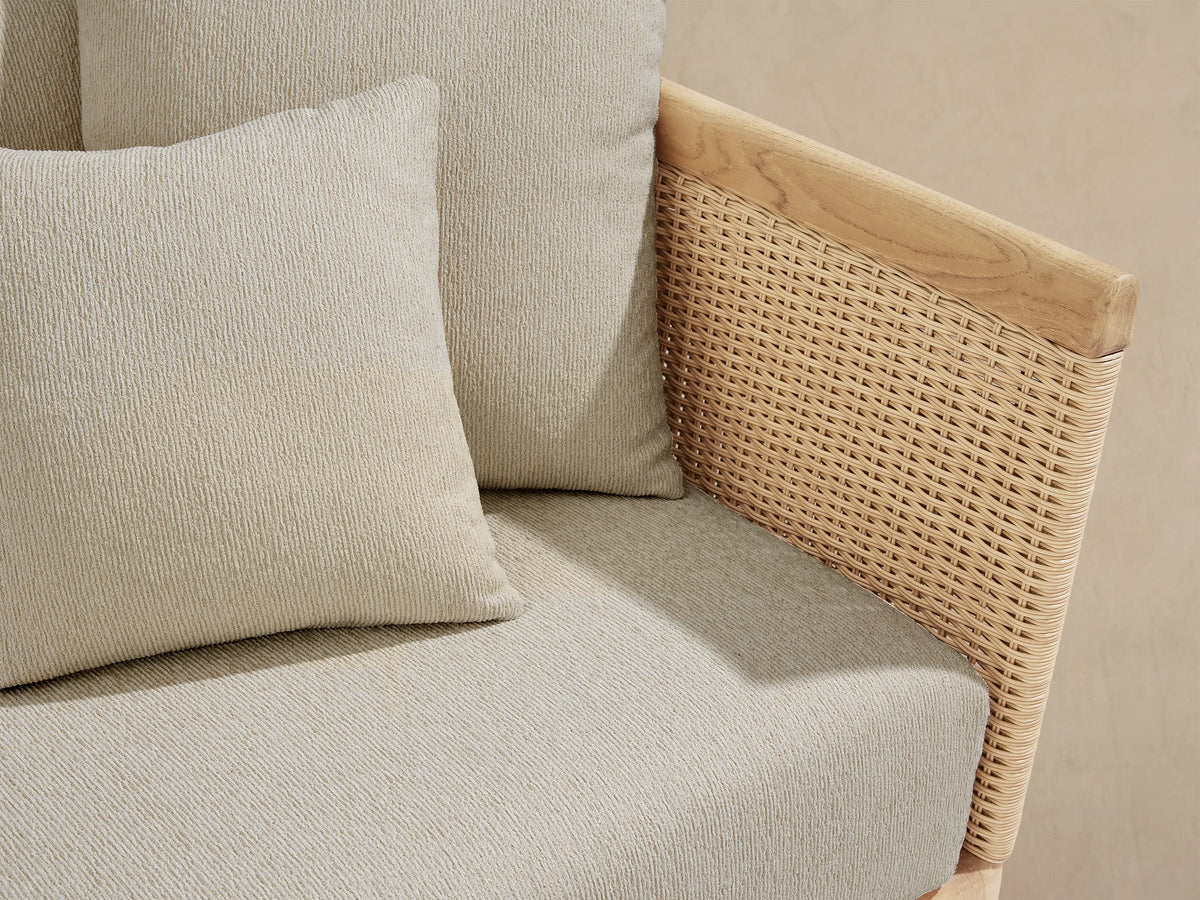 Puglia Outdoor Teak Two-Piece Sectional, L-shaped with light wood frame & wicker sides, cream cushions on a stone patio.