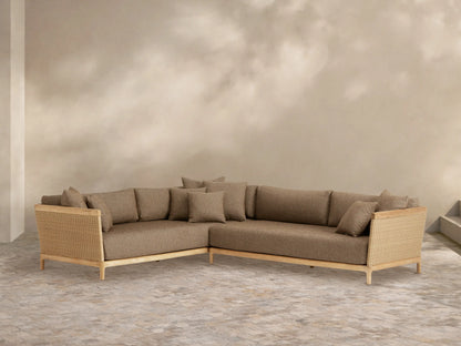 L-shaped Puglia Outdoor Teak Two-Piece Sectional with natural teak frame, woven wicker sides, and light brown cushions on a stone patio.