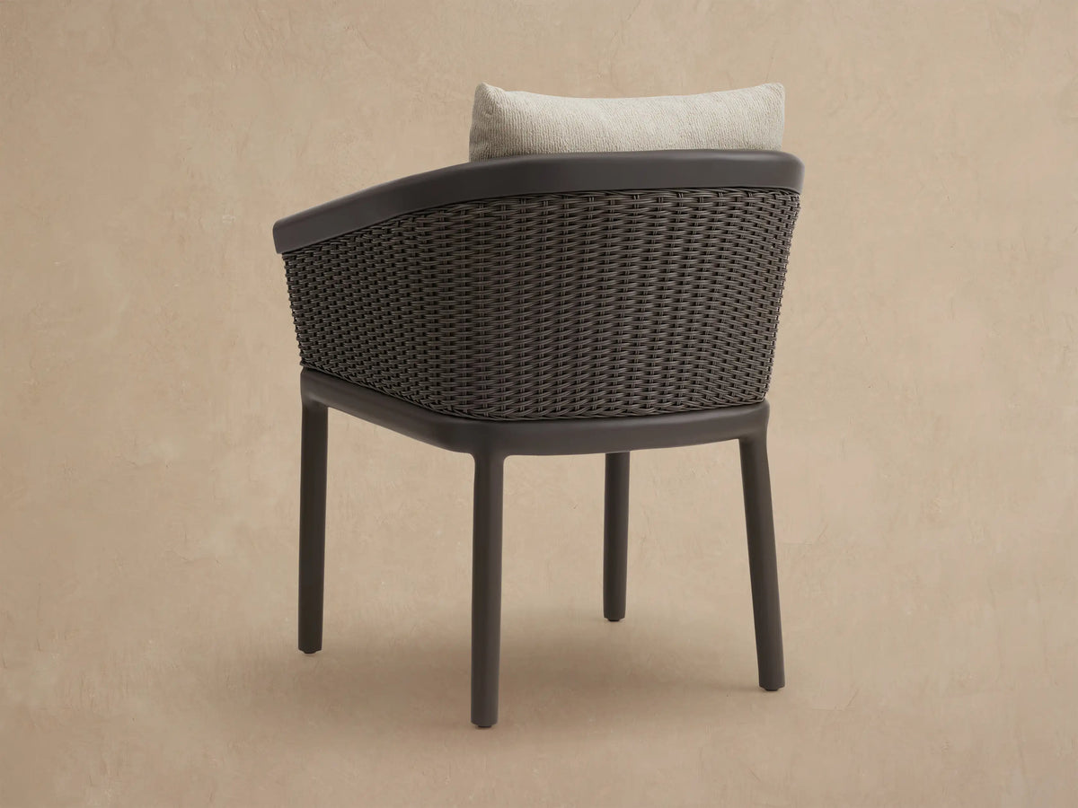 Angled close-up of Puglia Outdoor Aluminum Dining Chair: brown frame, dark brown woven wicker, and light beige textured cushions.