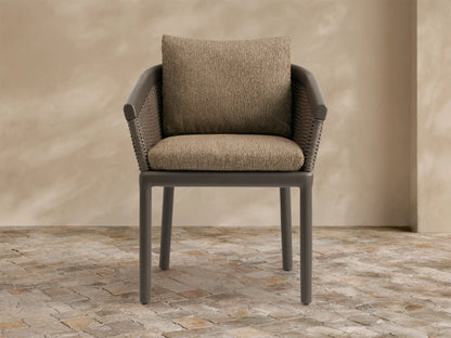 Puglia Outdoor Aluminum Dining Chair. Dark gray frame, brown woven wicker back/arms, and textured tan cushions on a patio.