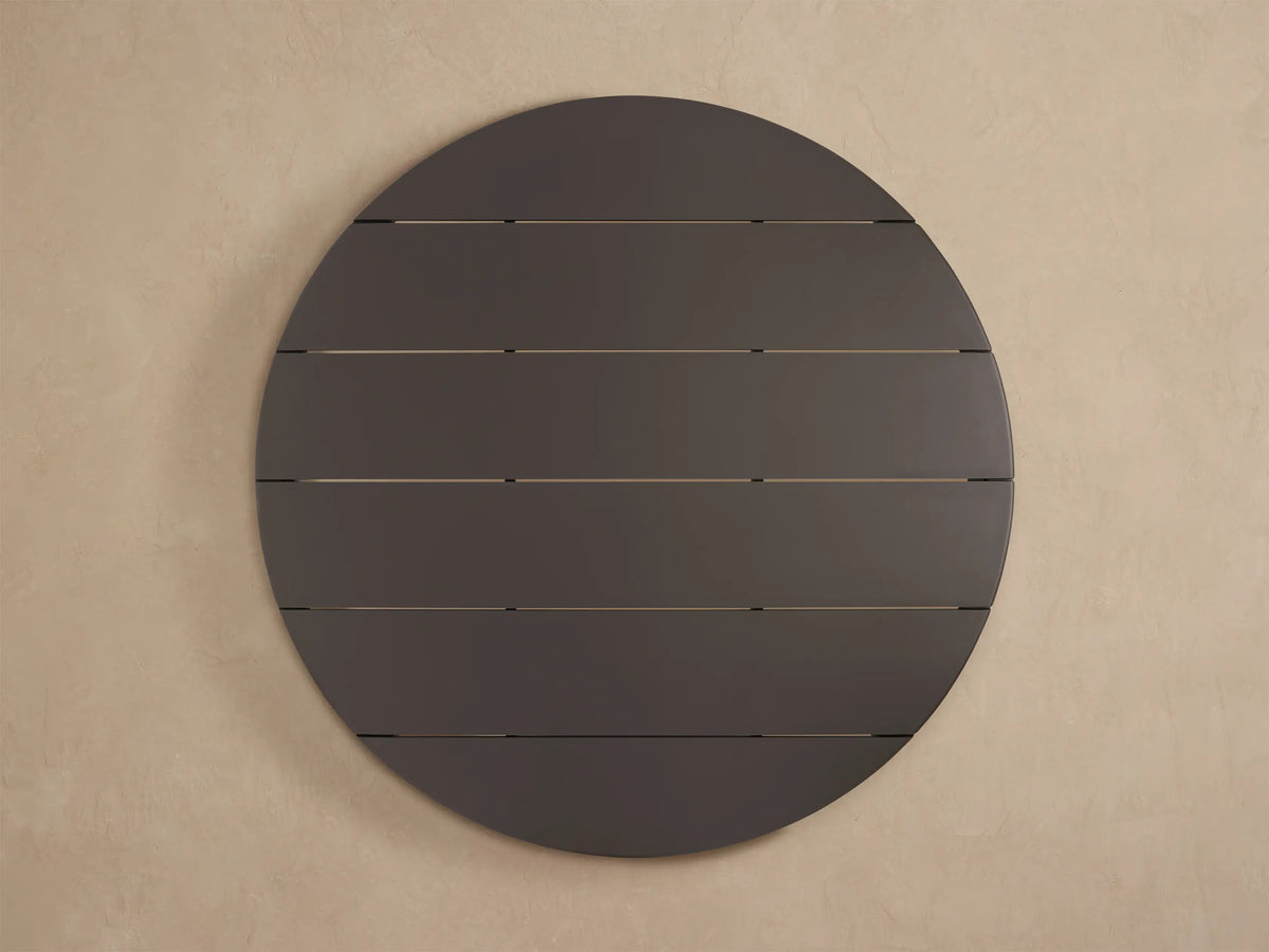Close-up of Puglia Outdoor Aluminum Round Dining Table. Dark gray matte slatted top with rounded edge and a leg, viewed from above.