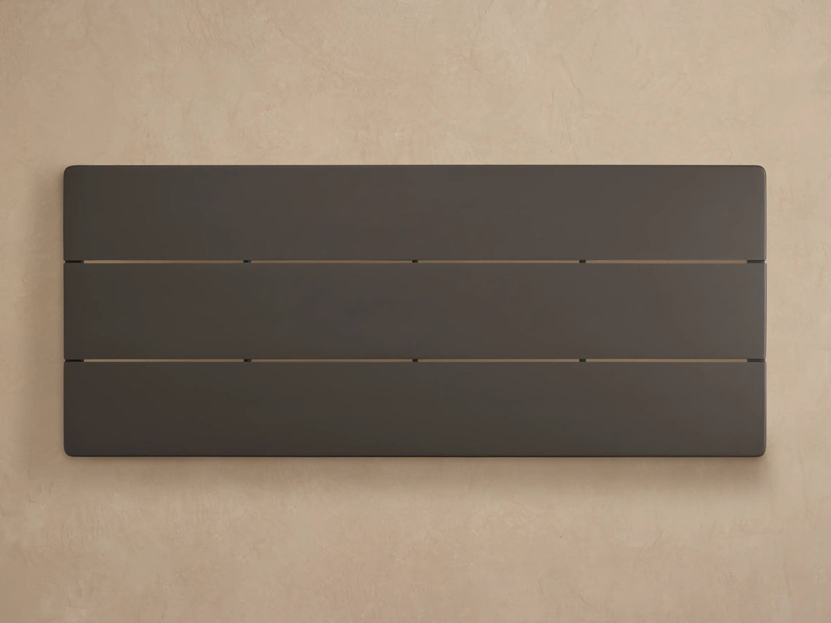 Angled close-up of the Puglia Outdoor Aluminum Coffee Table's dark bronze powder-coated top with slats and thick leg.