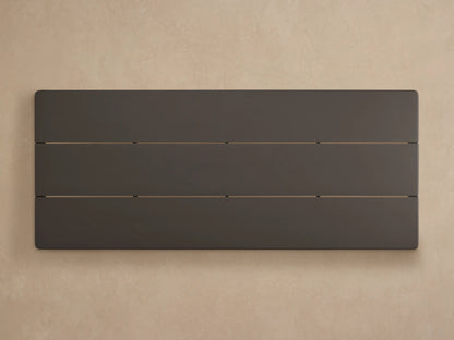 Angled close-up of the Puglia Outdoor Aluminum Coffee Table's dark bronze powder-coated top with slats and thick leg.