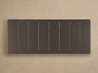Close-up, angled view of a dark gray Puglia Outdoor Aluminum Dining Table's rounded corner, with tabletop panel lines and sturdy leg.