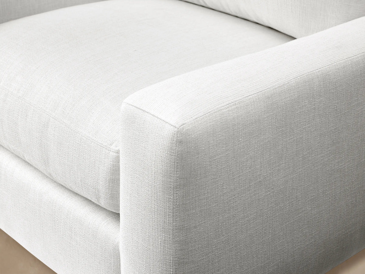 White Remington Outdoor Swivel Chair in Eden Snow fabric, front view, with plush cushions against a wooden shingle wall.