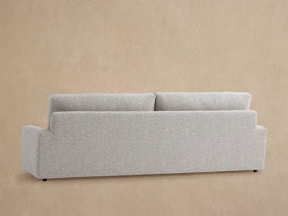 Remington Outdoor Sofa: Close-up of durable light gray textured fabric on armrest and backrest against a soft brown wall.