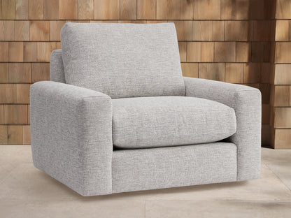 Light grey Remington Outdoor Swivel Chair with plush cushions, featuring square arms, set against a wooden shingle wall background.