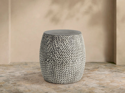 Roche Outdoor End Table, barrel-shaped, dark gray top, hand-textured sides with light gray organic pattern on patio.