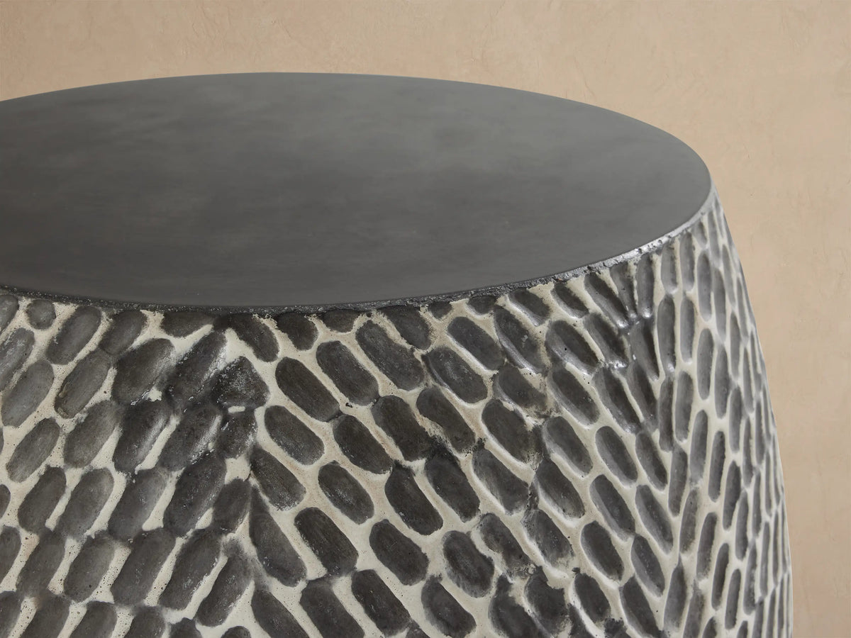 Roche Outdoor End Table, barrel-shaped, dark gray top, hand-textured sides with light gray organic pattern on patio.