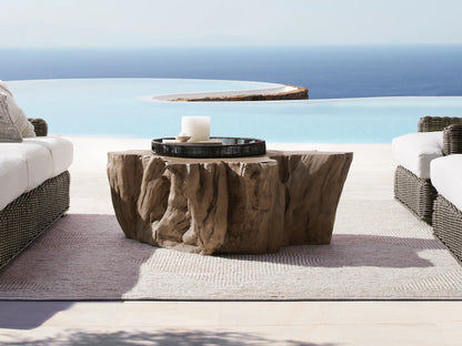 Root Outdoor Bleached Coffee Table with a textured, natural root-like surface beside an infinity pool and two white sofas.
