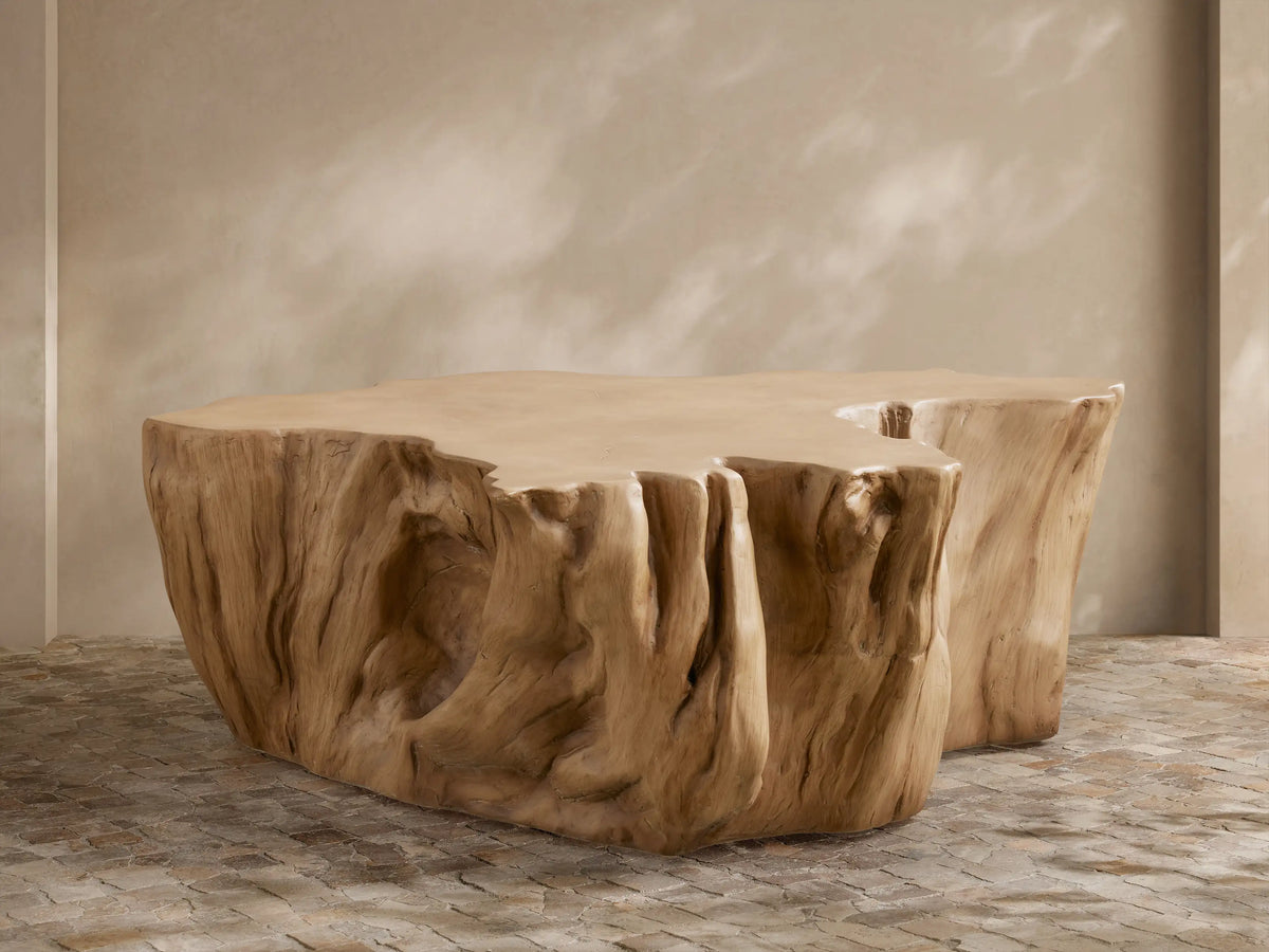 Root Outdoor Coffee Table, light brown concrete, sculpted like a tree root with textured sides, on a stone patio.