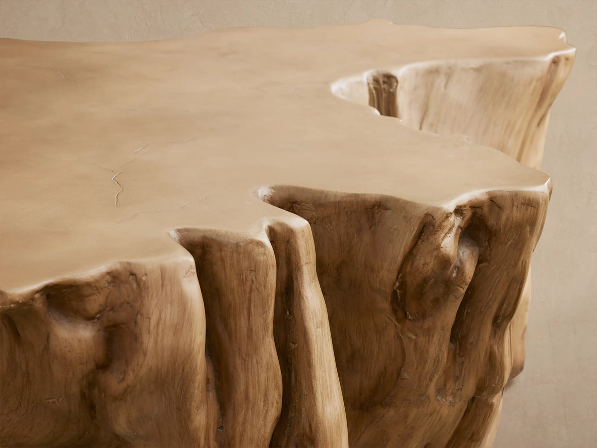 Root Outdoor Coffee Table, light brown concrete resembling a tree stump, with an organic shape, on a paved outdoor floor.