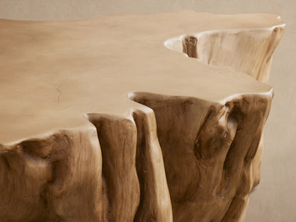 Root Outdoor Coffee Table, light brown concrete resembling a tree stump, with an organic shape, on a paved outdoor floor.