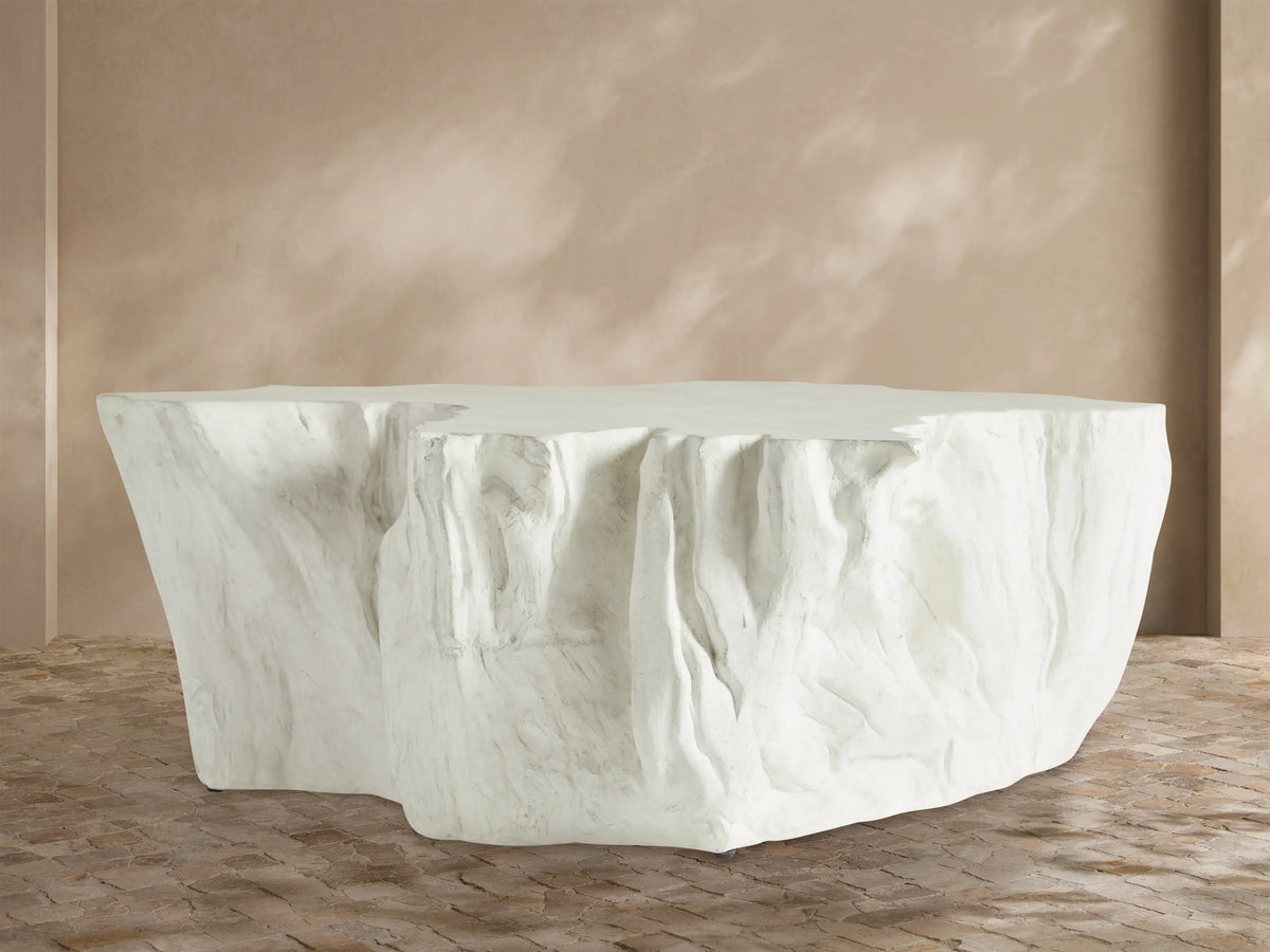 Bleached Root Outdoor Coffee Table, light concrete, organic shape, textured sides, flat top, on brick floor.
