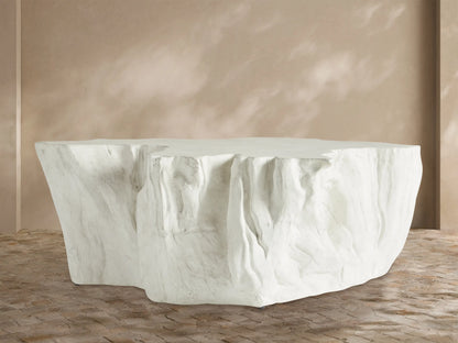 Bleached Root Outdoor Coffee Table, light concrete, organic shape, textured sides, flat top, on brick floor.